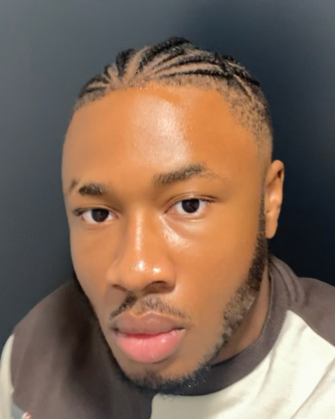 Ari, a nigerian male student wears a white and beige top and looks to camera